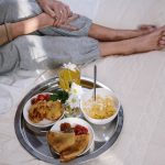 Cozy morning breakfast in bed featuring pancakes, fruit, and flowers. Perfect start to the day.